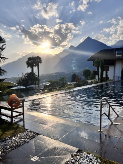 Hotel Hohenwart Südtirol – Außenpool bei Sonnenuntergang mit Blick auf die Berge und Palmen