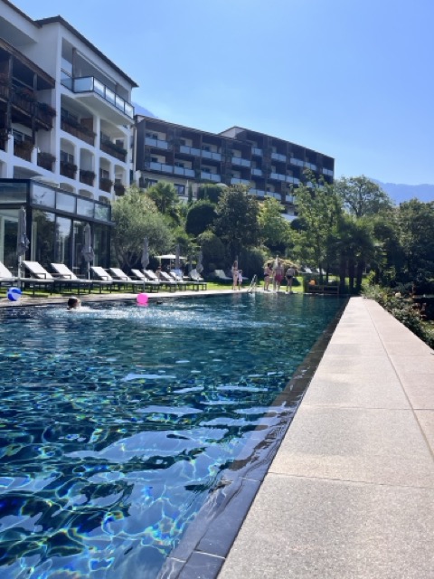 Hotel Hohenwart Südtirol – Infinity Pool mit Sonnenliegen und Gästen vor moderner Hotelkulisse