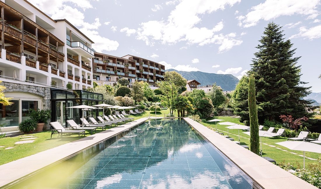 Familienhotel Hohenwart Südtirol – Außenansicht mit Pool und Garten, umgeben von Bergen, ideal für Wellnessurlaub und Familienauszeit.