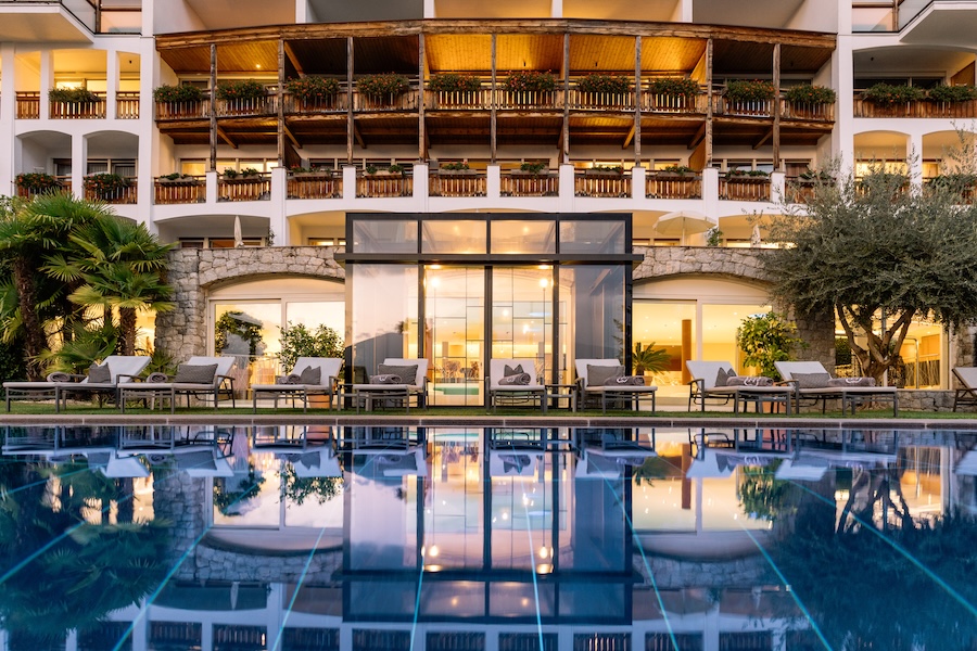 Hotel Hohenwart Südtirol – elegante Außenansicht mit Pool, Sonnenliegen und beleuchtetem Haupthaus am Abend